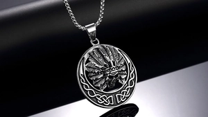 Détail d'un pendentif crâne argenté avec coiffe de plumes et nœuds celtiques sur fond noir