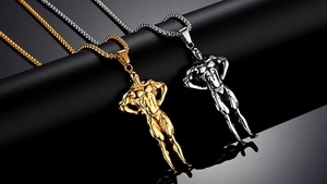 Dettaglio macro dei ciondoli bodybuilder in oro e argento su superficie nera lucida