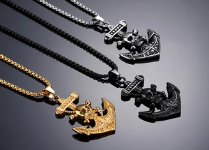 Trois pendentifs ancre et crâne en or, argent et noir sur une surface réfléchissante