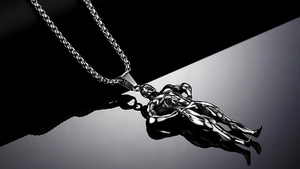 Dettaglio macro del ciondolo bodybuilder in argento con muscoli definiti e catena a scatola