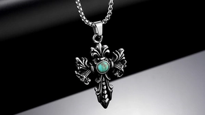 Macro detail of vintage steel cross pendant with turquoise inlay and ornate baroque carvings
