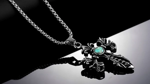 Macro shot of gothic cross pendant with turquoise inlay and polished box chain