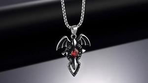 Macro shot of gothic bat wing pendant with red gemstone and vintage silver chain