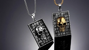 Detail view of punk skull rectangular pendant with intricate woven texture and steel chain