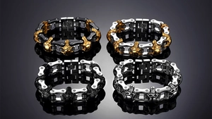 Detalle de pulseras de motero góticas con calaveras en acero inoxidable pulido y oro