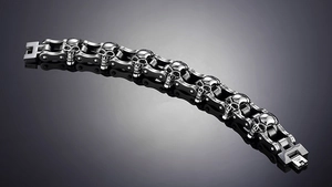 Detalle de los eslabones de cadena motera con calaveras talladas en acero inoxidable