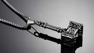Vue macro du pendentif Marteau de Thor avec motifs nordiques sur miroir noir poli