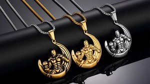 Three men's bodybuilding dumbbell pendants in gold and silver on black pedestals