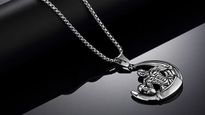 Macro detail of silver dumbbell pendant with crescent moon and muscular fitness male motif