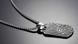 Close-up of silver stainless steel rectangular dog tag pendant with textured wood grain pattern