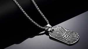 Close-up of rectangular silver stainless steel dog tag pendant with unique wood grain texture