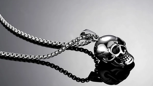 Macro shot of polished silver skull pendant with box chain in punk gothic style