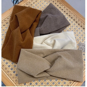 Lot de quatre bandeaux en tricot torsadé aux tons automnaux sur un fond en rotin rustique
