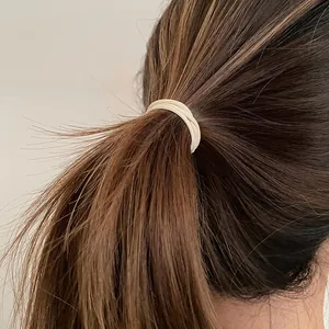 Détail d'un élastique beige haute élasticité pour queue de cheval avec texture tissée