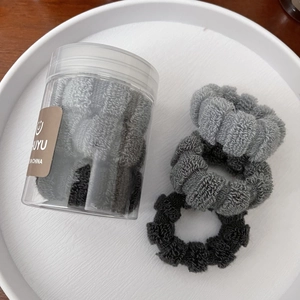 Close-up of high-elasticity thick terry hair ties in grey and black with storage jar