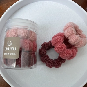 Close-up of three pink and burgundy elastic hair ties in a clear storage bottle