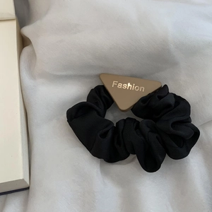 Detail of black satin scrunchie with khaki triangle buckle and golden Fashion lettering
