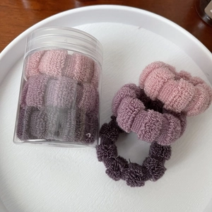Purple elastic hair ties set in a storage jar on a tray, stylish scrunchies for women