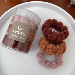 Detail of high-elasticity scrunchies in a clear storage jar on a white ceramic plate