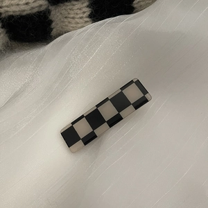 Gros plan sur la pince à cheveux rectangulaire à motif damier en acétate de qualité