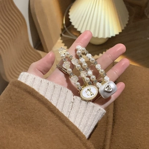 Détail de barrettes en perles avec fleurs blanches et accents dorés sur tricot