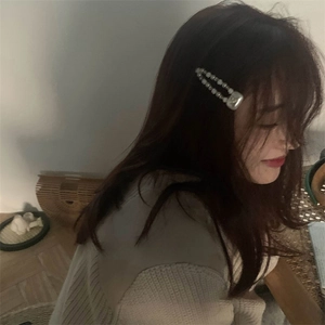 Détail d'une barrette à perles blanches avec base en métal argenté et motif cœur sur cheveux