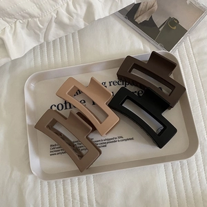 Set of four matte rectangular hair claws in black and coffee tones on a white tray