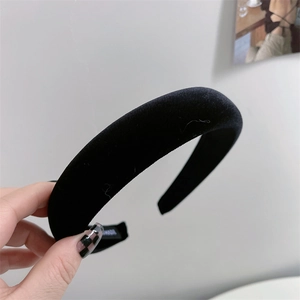 Close-up of black velvet padded headband with inner handmade label on grey background