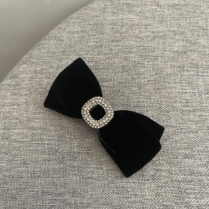Détail d'une barrette noeud en velours noir avec boucle carrée en strass au style vintage