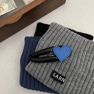 Detail of a black leather heart hair clip paired with cozy autumn winter knit beanies