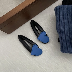 Detail view of heart-shaped hair clips with blue silicone accents and black leather base