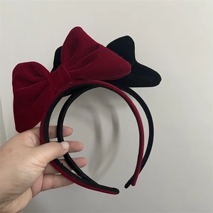 Close-up of vintage velvet bow headbands in burgundy and black with glossy texture