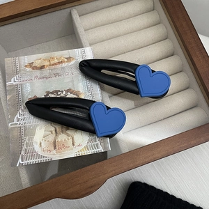 Detail shot of heart-shaped blue and black PU leather hair clips on velvet display