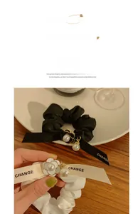 Close-up of satin scrunchies with camellia flower, pearl charm and CHANGE ribbon