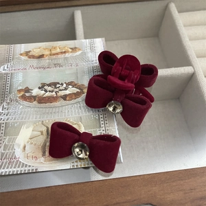 Detailed view of burgundy velvet bow hair clip with central sparkling crystal accent