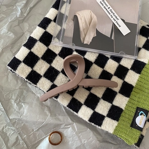 Brown matte large hair claw clip on checkerboard scarf background with decorative items