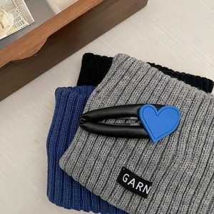 Blue heart leather hair clip and knitted winter accessories on a wooden background