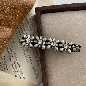Pasador vintage barroco con perlas y diamantes en una caja de joyas de terciopelo marrón