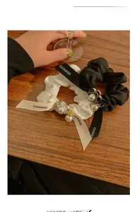 Detail of satin hair scrunchies with camellia charm, pearls, and ribbon lettering