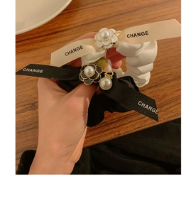 Detail of satin scrunchies featuring camellia flower and Change ribbon bow ties
