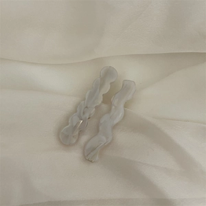 Détail de pinces à cheveux vagues marbre blanc sur soie beige, barrettes en acétate
