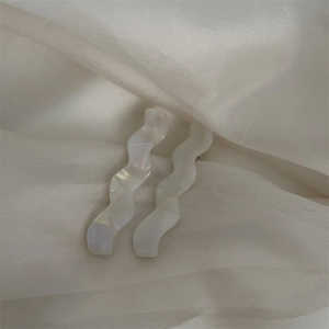 Gros plan de barrettes à cheveux ondulées nacrées sur fond de tissu en soie blanche