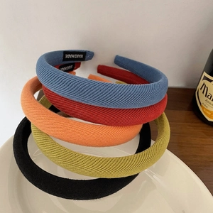 Détail de serre-têtes en éponge colorés montrant le tissu côtelé et l'étiquette faite main