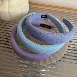 Close-up of three thick sponge headbands in pastel colors featuring a Hand Made label