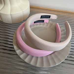 Detail of pink and beige sponge headbands with handmade tags on a ceramic tray