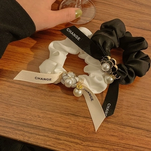 Elegant camellia bow scrunchies set with pearls and ribbons on a wooden background