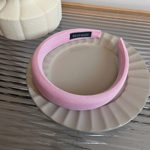 Close-up of pink padded sponge headband with handmade label on a stylish beige tray