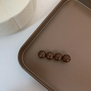 Detailed close-up of dark brown spherical beads on a minimalist metallic hair clip
