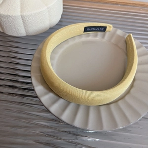 Detail of light yellow knit fabric headband with thick sponge and handmade label