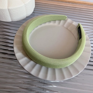 Detailed close-up of grass green padded sponge headband featuring a Hand Made label